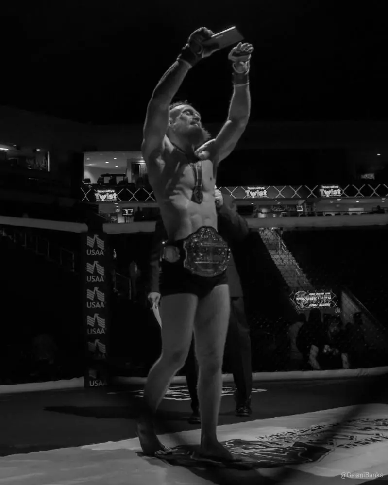 Chris holds his belt overhead in the arena
